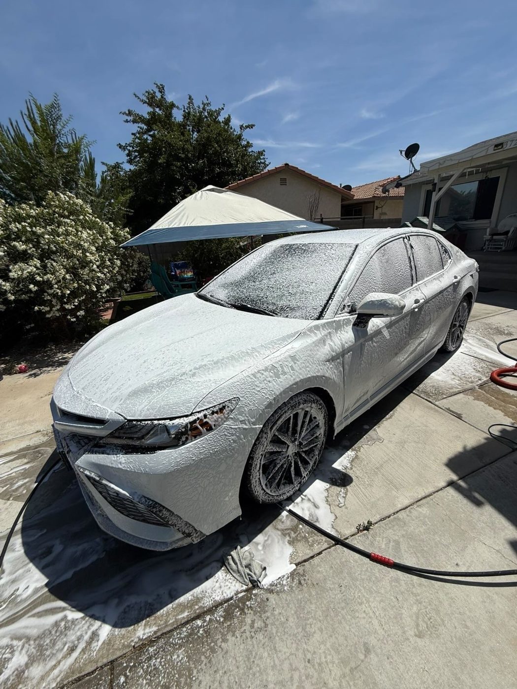 Sedan covered in thick foam during an exterior wash